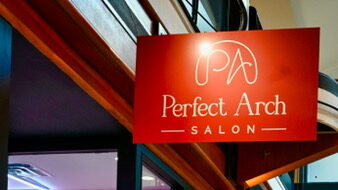 Pink-toned salon interior with velvet styling chairs and lit mirrors